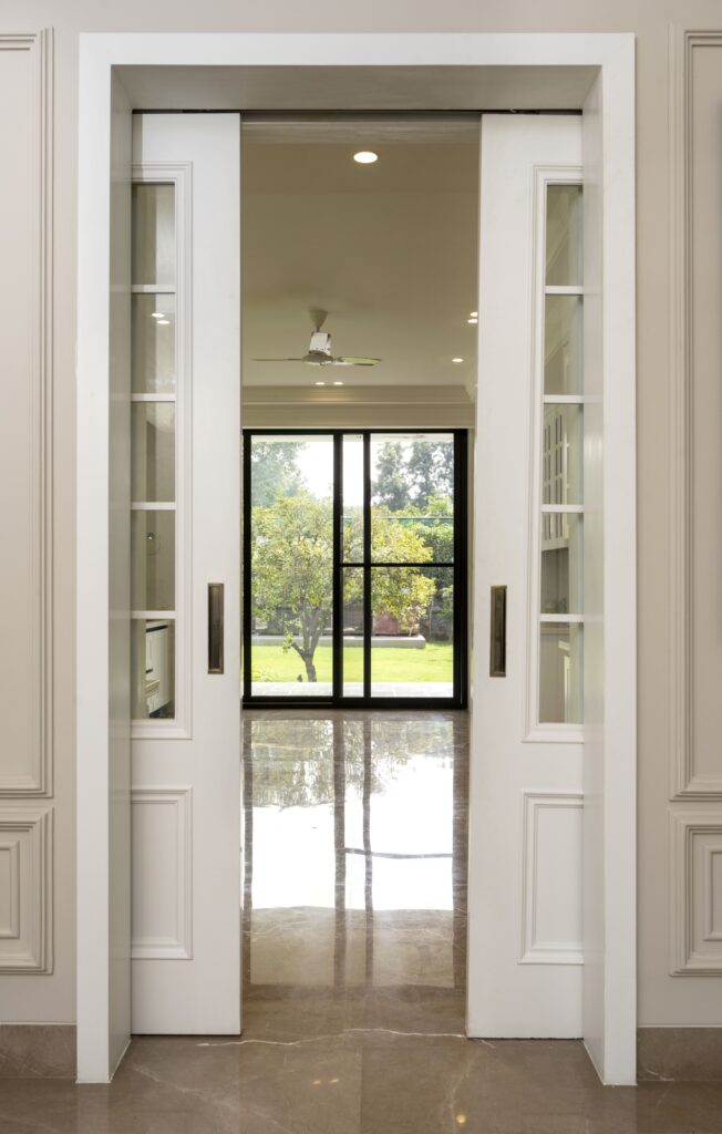 French pocket doors separating the kitchen from the dining area at Maison Grise by Pochē Aesthetics